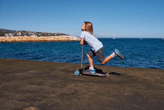 Boy riding a scooter on a pier at sunny day