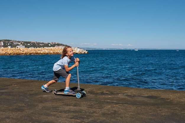 Boy riding a scooter on a pier at sunny day