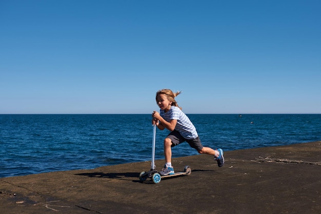 Boy riding a scooter on a pier at sunny day