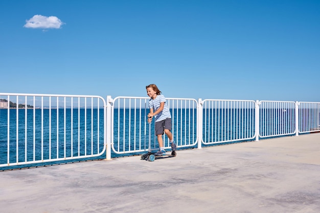 Boy riding a scooter on a pier at sunny day