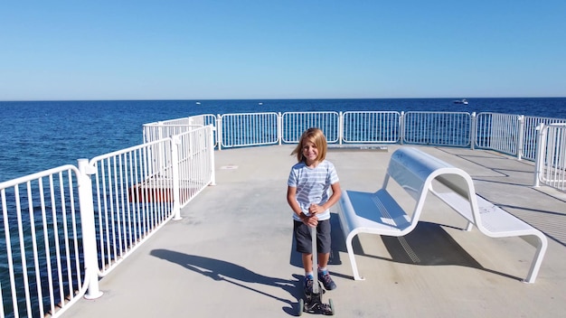 Boy riding scooter on a pier at sunyday