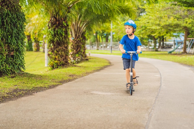 Boy riding scooters outdoor in the park summertime Kids are happy playing outdoors