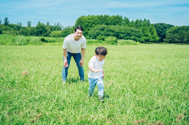 A boy running in the meadow and a father watching over