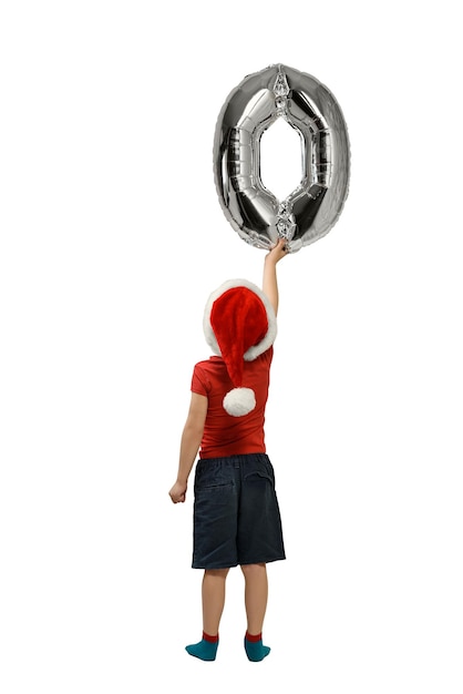 Boy in Santa hat holds up silver inflatable digit zero Back view Isolated on white background