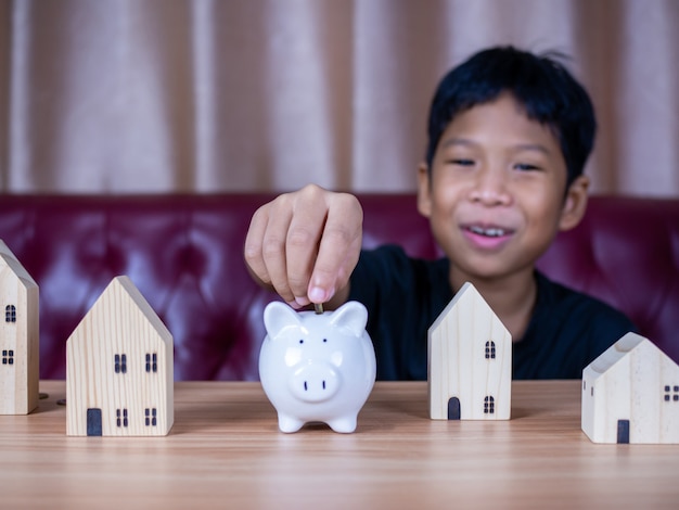 Boy saving money in a white pig piggy bank.Saving concept. Saving for the future.