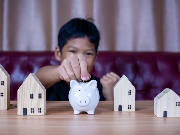 Boy saving money in a white pig piggy bank.Saving concept. Saving for the future.