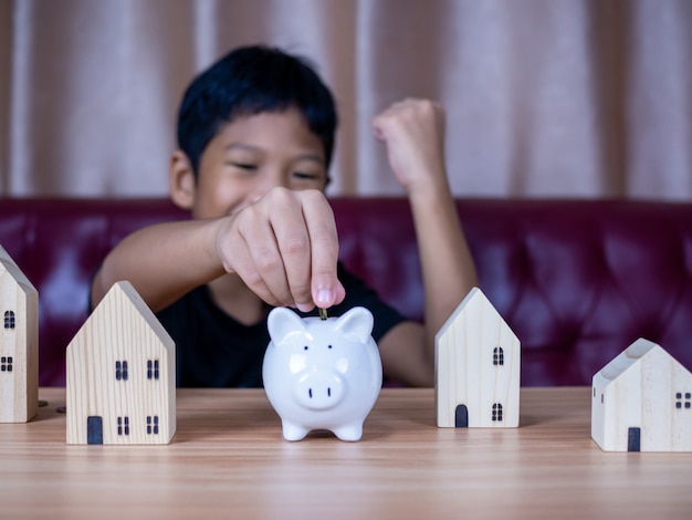 Boy saving money in a white pig piggy bank.Saving concept. Saving for the future.