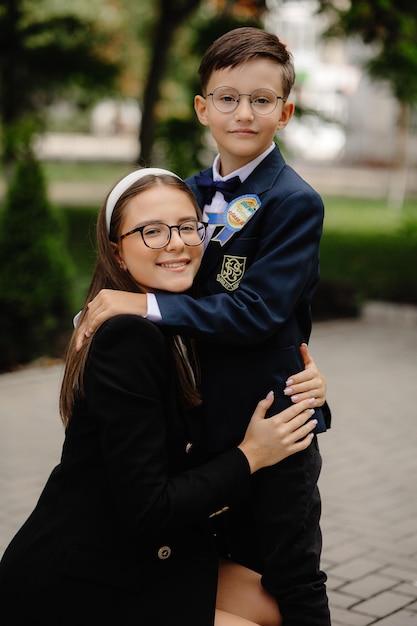 A boy in a school uniform hugs a young boy