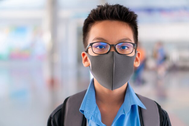 Boy in school uniform wearing a surgical mask with blurred background, Virus protection concept.