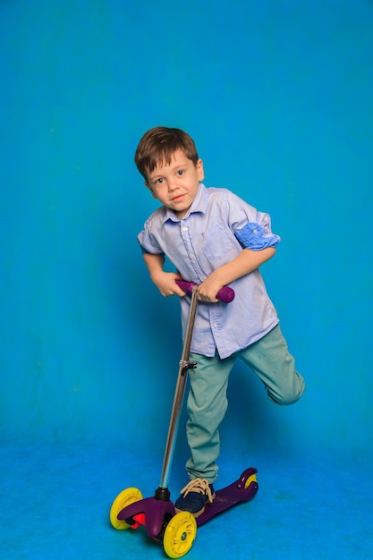 A boy on a scooter on a blue background An article about children's scooters An article about the choice of a scooter for a child A happy child Blue background and a boy