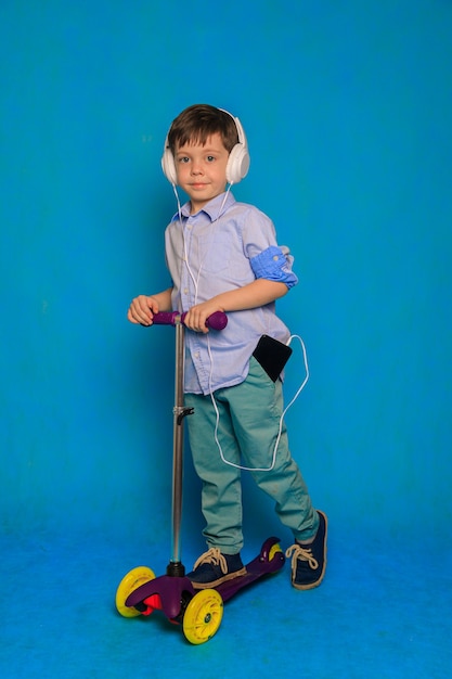 A boy on a scooter with headphones on a blue background  An article about childrens scooters