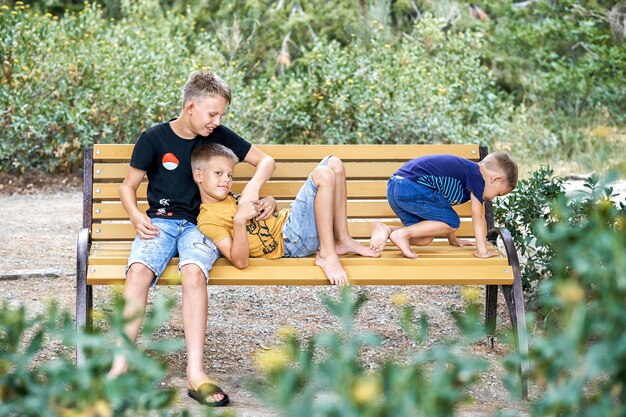 Boy siblings enjoy playing together sitting on wooden bench in park