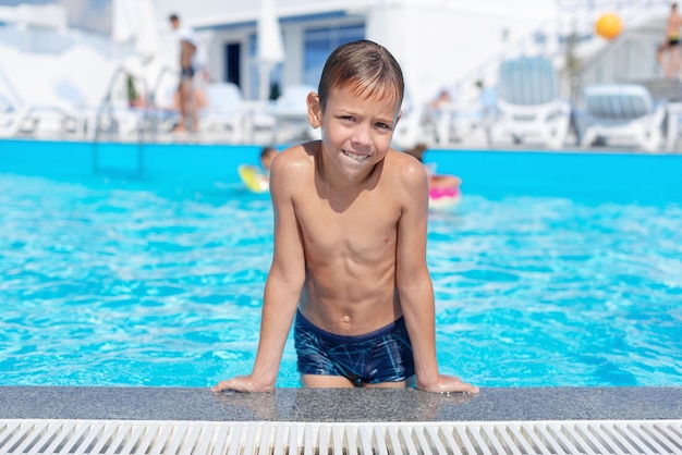 The boy on the side of the pool is smiling The open air swimming pool