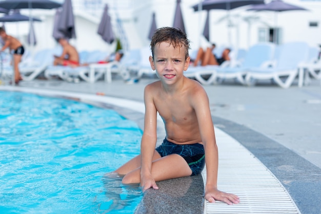 The boy on the side of the pool is smiling The open air swimming pool