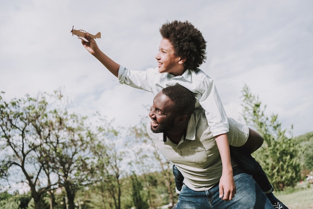 Boy Sitting on Afro Father Back and Play with Plane