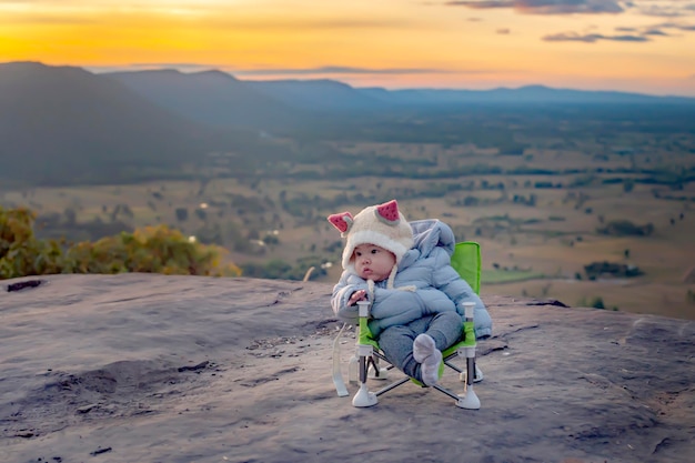 Boy sitting on a beautiful mountain view at sunrise in winter