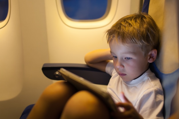 Boy sitting in the plane and using tablet PC