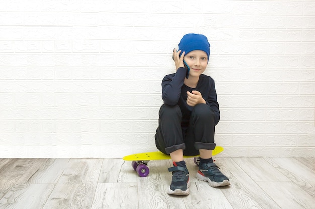 Boy sitting on a skateboard and talking on the phone