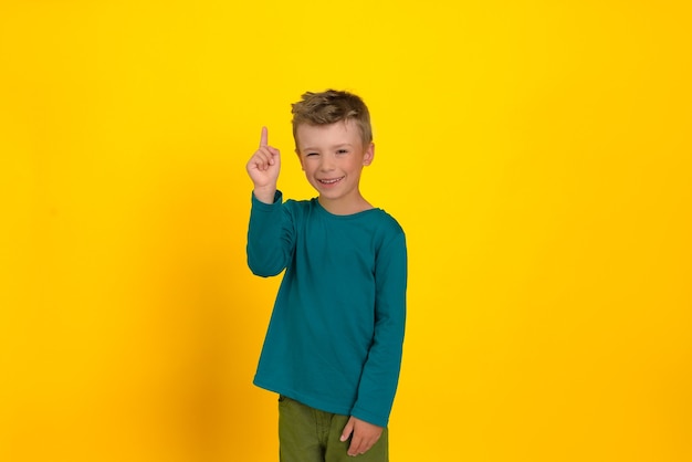 A boy smiles and shows with a hand gesture that he has an idea by raising his index finger upwards