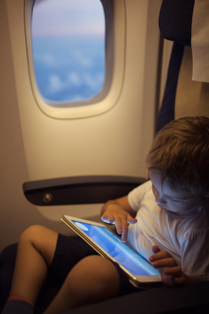 Boy spending time with tablet PC during flight