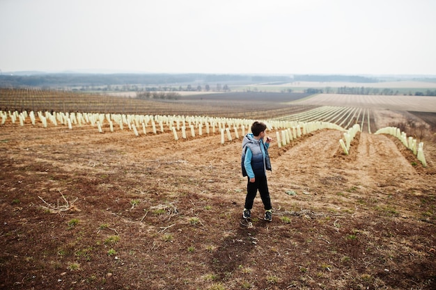 Boy stand against vineyard in early spring