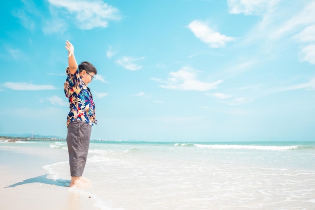 Boy standing on the beach during the summer time enjoying the view