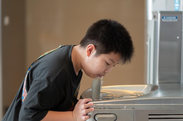 Boy standing drinking water from a water dispenser