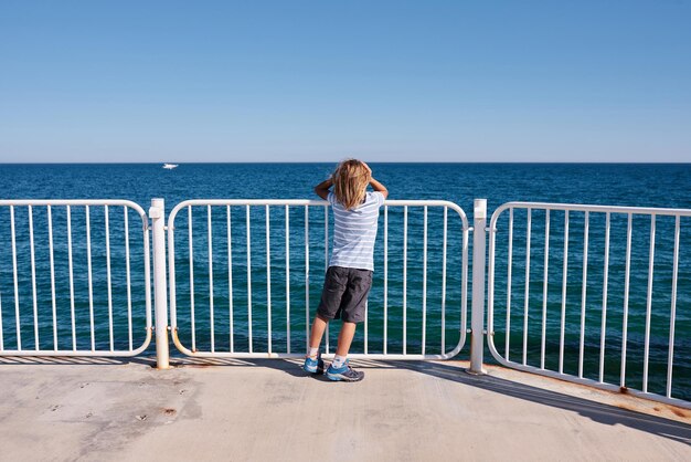 Boy standing on a pier at sunny day