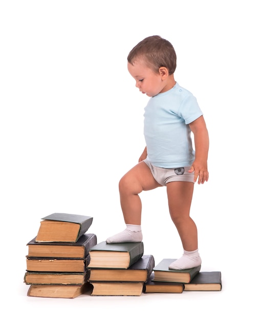 Boy stands on stack of books for educational portrait - isolated over white surface