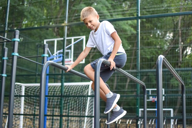 boy on street sports does gymnastic exercises. City outdoor sports ground.