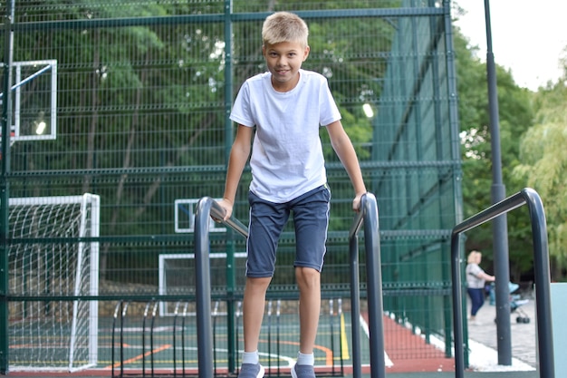 boy on street sports does gymnastic exercises. City outdoor sports ground.