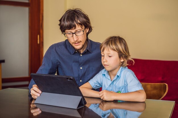 Boy studying online at home using a tablet Father helps him learn Studying during quarantine Global pandemic covid19 virus