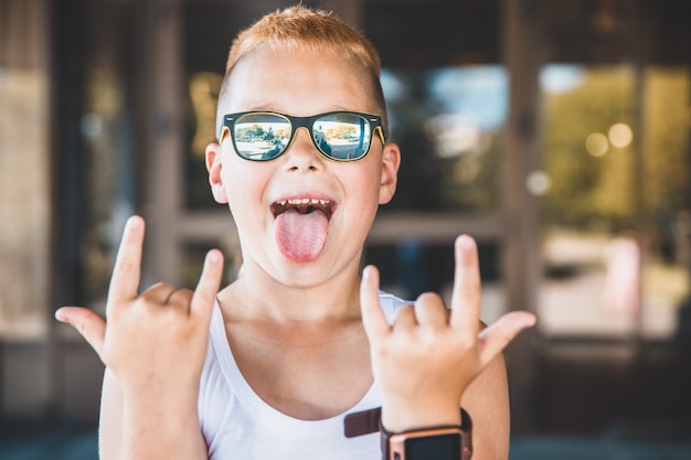 Boy in sunglasses sticks out his tongue.