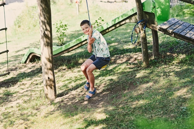 Boy swinging on a rope against slide in mountain village