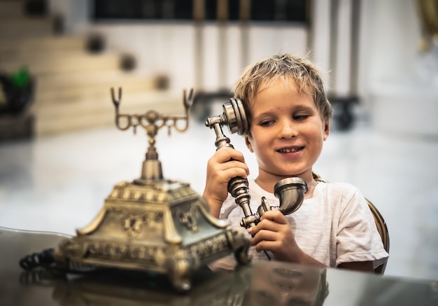 Boy take telephone receiver play with antique vintage rotary old landline hang up phone beautifully embossed gold bronze texture retro style Concept of wealth prosperity beauty of last century art