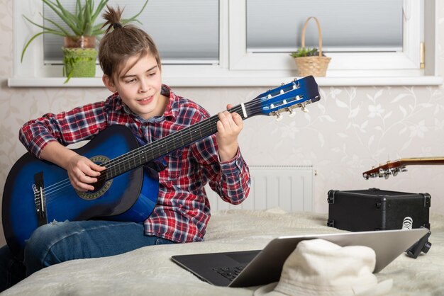 Boy teenager playing guitar at home