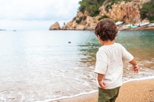 A boy throwing stones on the beach of the port of Sant Miquel Ibiza Island Balearic Islands