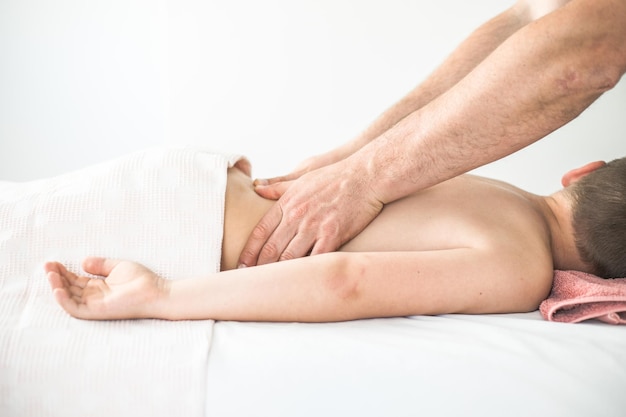 Boy toddler relaxes from a therapeutic massage Physiotherapist working with patient in clinic to treat the back of a child