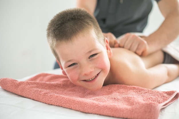 Boy toddler relaxes from a therapeutic massage Physiotherapist working with patient in clinic to treat the back of a child