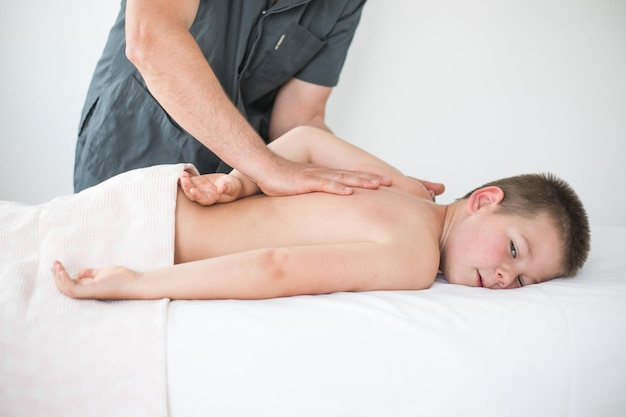 Boy toddler relaxes from a therapeutic massage Physiotherapist working with patient in clinic to treat the back of a child