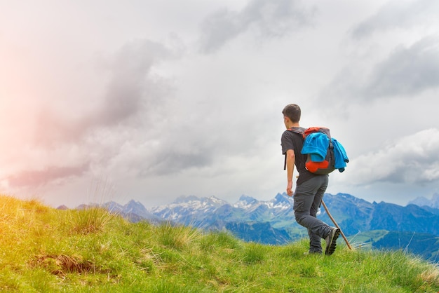 Boy walking in the mountains with his stick in the meadows