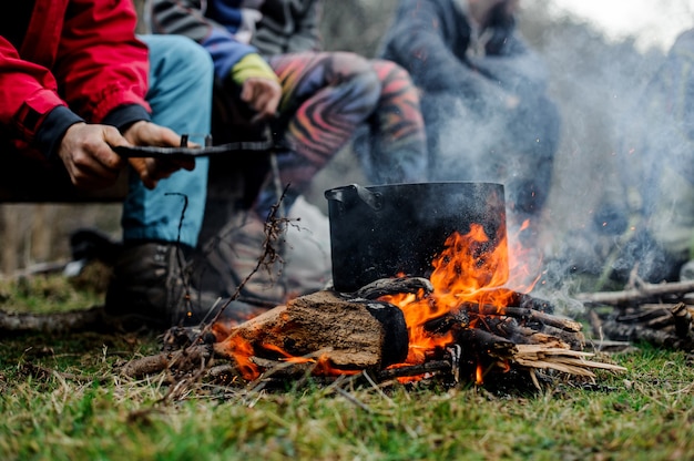 Boy waving a blow on the pan on the bonfire over the group of friends