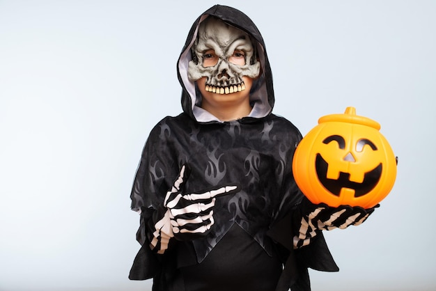 A boy wearing halloween costume with pumpkin basket on blue background