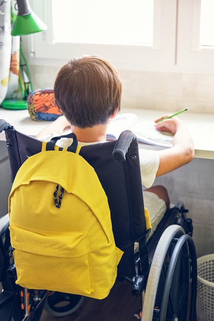 Boy in wheelchair doing homework in his room