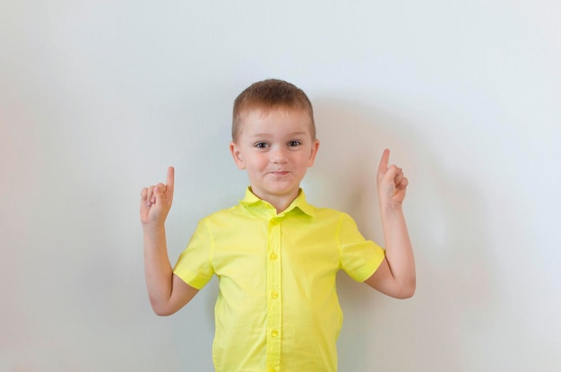 A boy on a white background shows his thumbs up Copy space