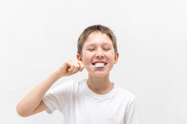 A boy in a white t-shirt is brushing his teeth in the bathroom