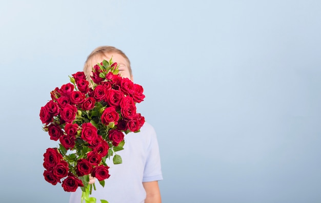 Boy with a bouquet of red roses as gift for Mother's day or Valentine's day