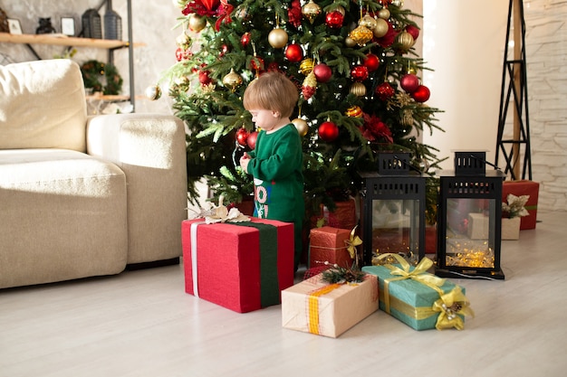 Boy with Christmas presents next to tree