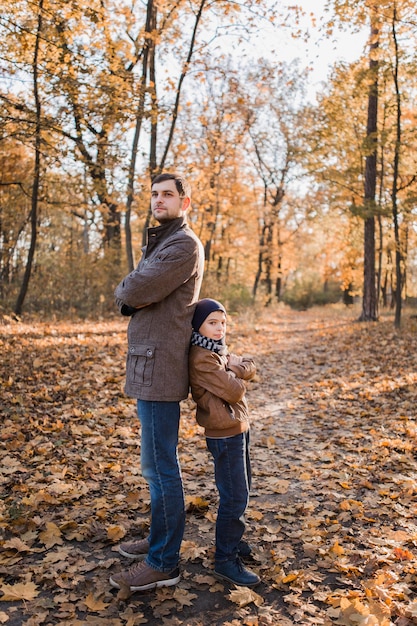 Boy with dad in autumn forest with orange leaves