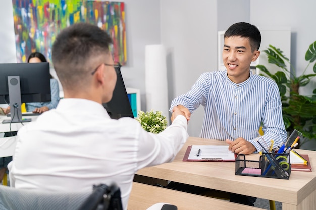 boy with disability arrives in wheelchair boss sitting across from him shakes hands